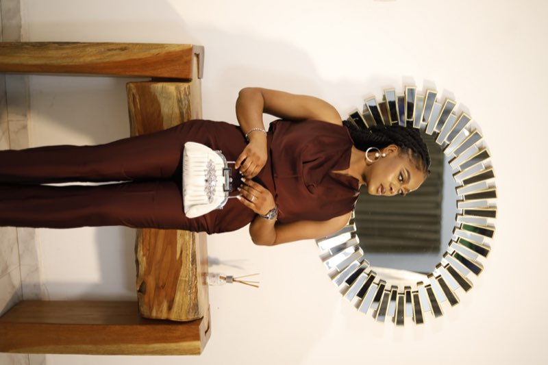 Burgundy cowl-neck sleeveless top with matching tailored trousers and white beaded clutch by Prom G Fashion Enugu