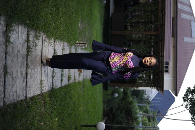 Navy bell-sleeve jumpsuit with pink purple Ankara corset overlay garden walkway by Prom G Fashion