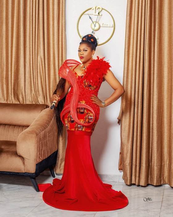 Red mermaid gown with feathered shoulder and Ankara panels by Prom G Fashion Enugu